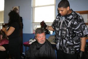 Brandon Merriweather cuts the hair of one of the men who came to the event at the New Life Day Center.  PHOTO: Avis Sampson, UK senior